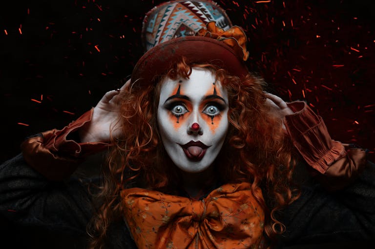 Colorful clown with stage makeup and top hat, playfully posing with a dramatic expression.
