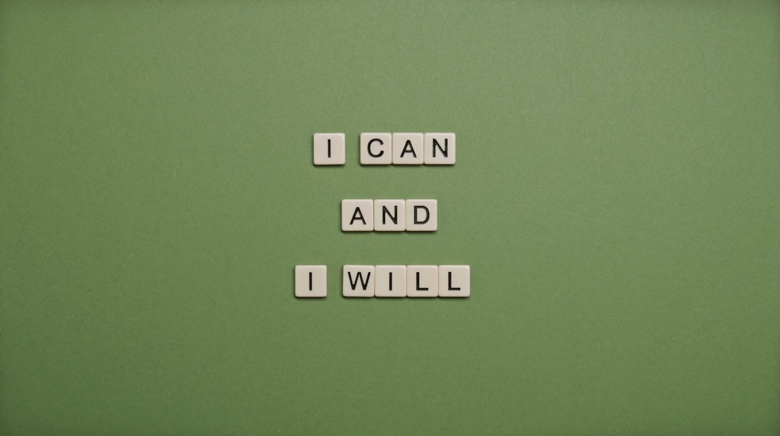 Inspirational message 'I Can and I Will' spelled with tile letters on a green background.