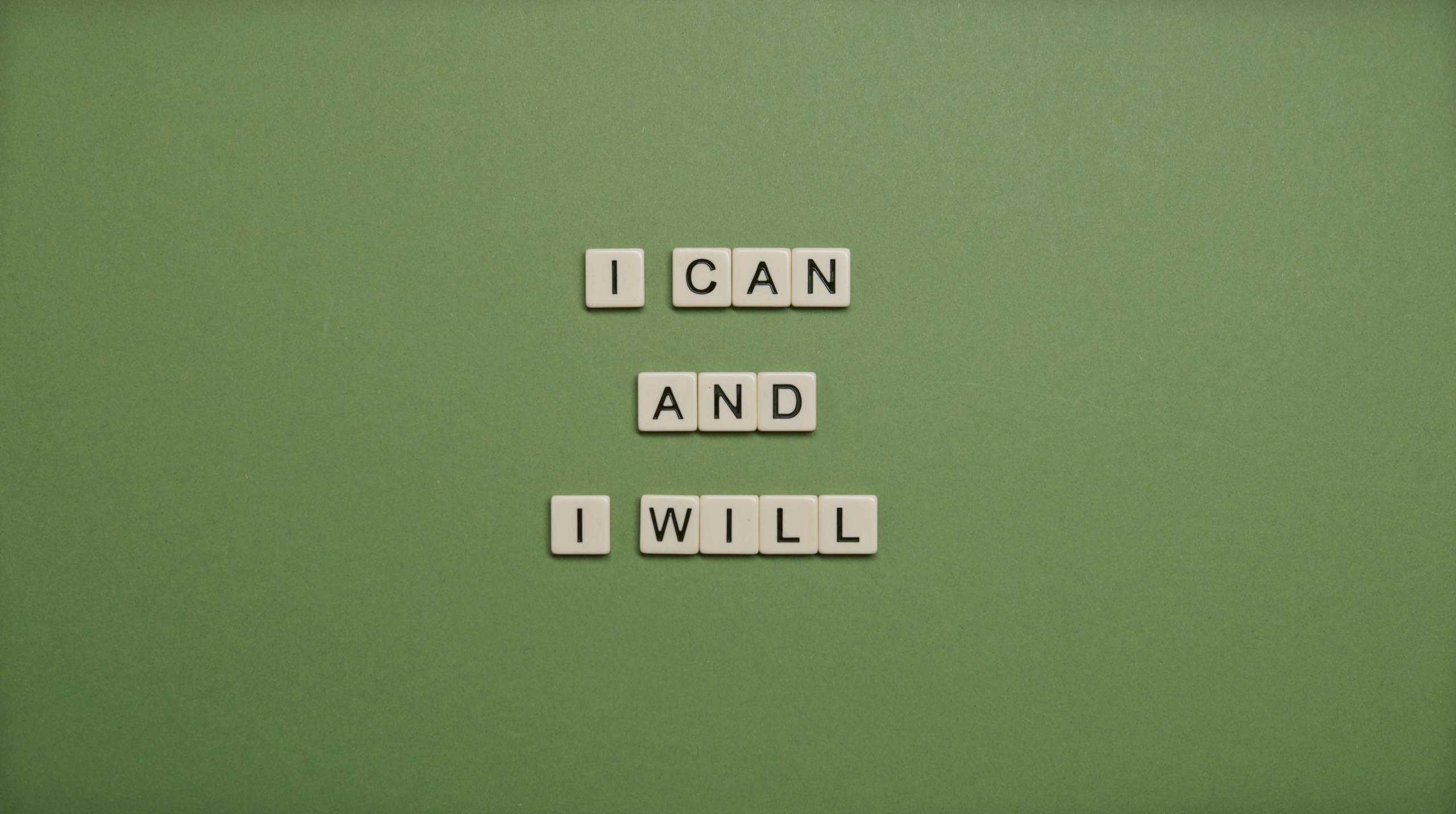 Inspirational message 'I Can and I Will' spelled with tile letters on a green background.