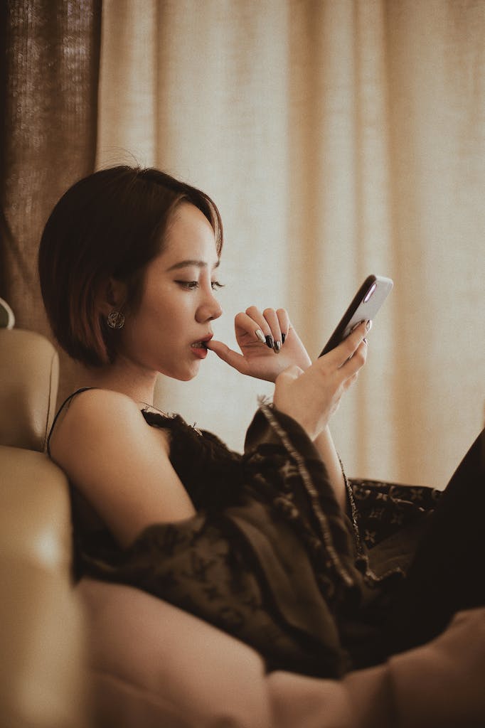 Woman lounging indoors, focused on her smartphone, enjoying leisure time.