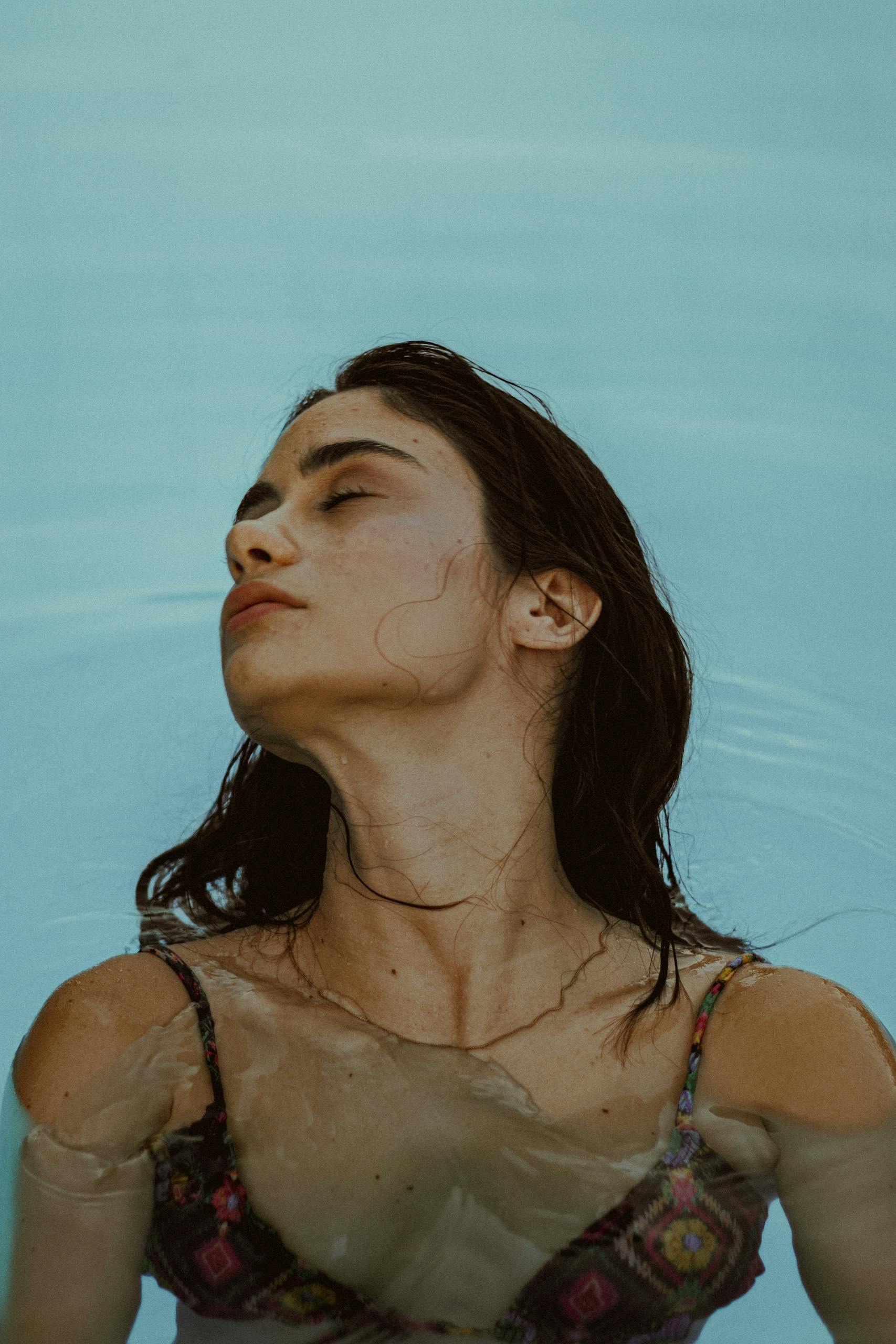 Portrait of a woman in a bikini floating calmly in a pool, showcasing relaxation and summer vibes.